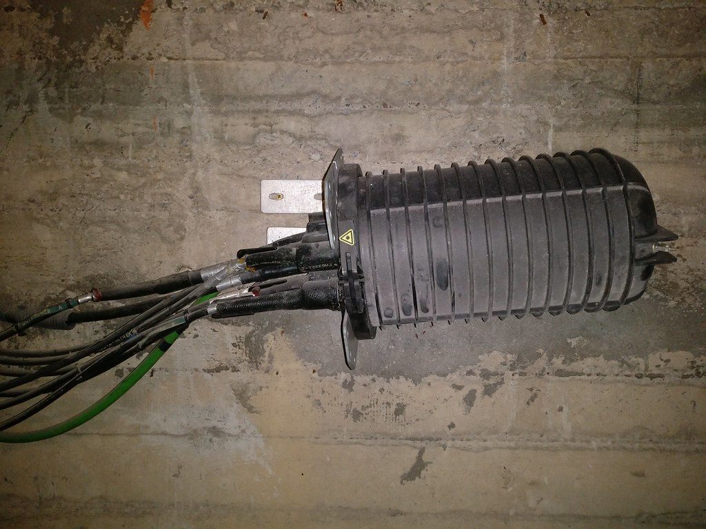 A dome-style fiber optic splice closure mounted in a vault with several armored cables entering through the base seals